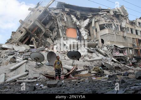 (210513) -- CITTÀ DI GAZA, 13 maggio 2021 (Xinhua) -- UN ragazzo palestinese ispeziona le macerie della torre distrutta di al-Sharouk dopo gli attacchi aerei israeliani nella città di Gaza, 13 maggio 2021. La tensione tra Israele e i gruppi militanti nella striscia di Gaza è proseguita giovedì, mentre i funzionari del ministero della sanità gestito da Hamas hanno affermato che il numero delle vittime nell'enclave costiera assediata è salito a 83. Il ministero della salute a Gaza ha detto in un breve messaggio di testo inviato ai giornalisti che dall'inizio della tensione di lunedì, 83 palestinesi sono stati uccisi, tra cui 17 bambini e sette donne, aggiungendo che 487 sono stati feriti. (P Foto Stock