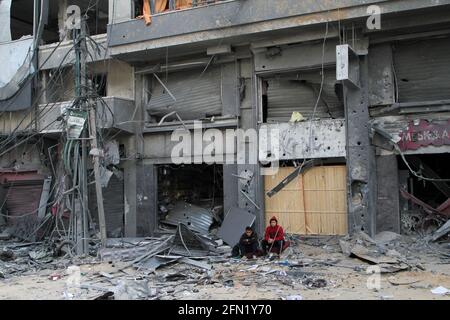 (210513) -- CITTÀ DI GAZA, 13 maggio 2021 (Xinhua) -- i palestinesi siedono fuori da un edificio danneggiato a seguito di attacchi aerei israeliani a Gaza, 13 maggio 2021. La tensione tra Israele e i gruppi militanti nella striscia di Gaza è proseguita giovedì, mentre i funzionari del ministero della sanità gestito da Hamas hanno affermato che il numero delle vittime nell'enclave costiera assediata è salito a 83. Il ministero della salute a Gaza ha detto in un breve messaggio di testo inviato ai giornalisti che dall'inizio della tensione di lunedì, 83 palestinesi sono stati uccisi, tra cui 17 bambini e sette donne, aggiungendo che 487 sono stati feriti. (Foto di Rizek Abdeljawad/Xin Foto Stock