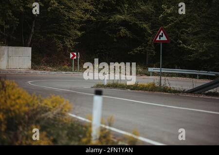 Strada tortuosa con cartelli in una foresta rurale Foto Stock