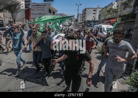 Gaza, territori palestinesi. 13 maggio 2021. I lutto frequentano i funerali di 13 combattenti del movimento islamista Hamas, che sono stati uccisi negli attacchi aerei israeliani sulla città di Gaza. Il Ministero della Sanità della striscia di Gaza ha affermato oggi, giovedì, che il numero di morti palestinesi è salito a 83 in mezzo a una riacutizzazione della violenza israelo-palestinese. Credit: Mohammed Talatene/dpa/Alamy Live News Foto Stock