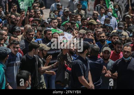 Gaza, territori palestinesi. 13 maggio 2021. I lutto frequentano i funerali di 13 combattenti del movimento islamista Hamas, che sono stati uccisi negli attacchi aerei israeliani sulla città di Gaza. Il Ministero della Sanità della striscia di Gaza ha affermato oggi, giovedì, che il numero di morti palestinesi è salito a 83 in mezzo a una riacutizzazione della violenza israelo-palestinese. Credit: Mohammed Talatene/dpa/Alamy Live News Foto Stock