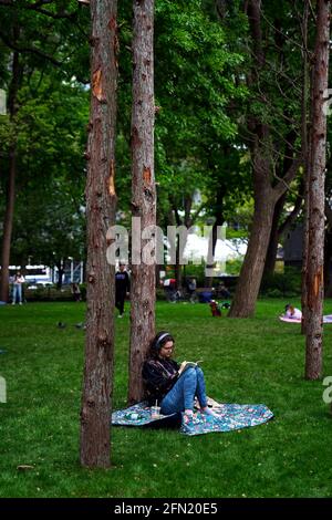 New York City, New York, 13 maggio 2021: I visitatori siedono tra la Ghost Forest, un'installazione sensibile dell'artista e designer Maya Lin, nel Madison Square Park di New York il giorno della sua apertura al pubblico. L'installazione consiste di quarantanove alberi di cedro bianchi dell'Atlantico, vittime dell'inondazione di acqua salata, è destinata ad essere un simbolo sia della devastazione del cambiamento climatico e della perdita di foreste in tutto il mondo, e di appello ad un'azione individuale. Credit: Adam Stoltman/Alamy Live News Foto Stock