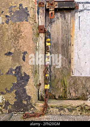 Vecchio porta in legno disusato con una catena arrugginita che si incoda via Foto Stock