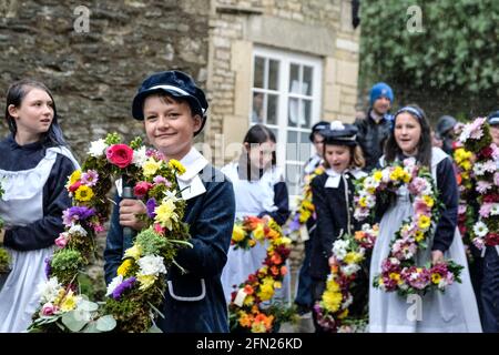 Bisley, Glos, Regno Unito. 13 maggio 2021. Ritorno alle attività tradizionali del Cotswold. I bambini della scuola primaria Blue Coat celebrano il giorno dell'Ascensione sfilando attraverso il villaggio fino alle Wells e poi decorarli con fiori. La tradizione iniziò nel 1863 quando il Vicario, il reverendo Keble, rese grazie per l'acqua pulita dei villaggi. Credit: JMF News/Alamy Live News Foto Stock