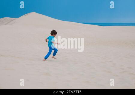 Ragazzo giovane con un vestito blu acceso nella sabbia attraverso la duna del Pyla, Gironde (33), Nouvelle-Aquitaine, Francia Foto Stock