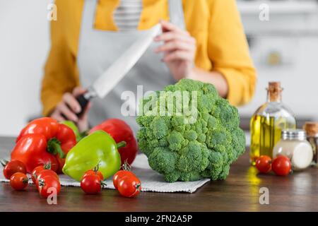 verdure mature vicino alla donna con coltello su sfondo sfocato Foto Stock