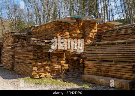 Lotti di assi di legno accatastati su un cortile di legname dentro ambiente soleggiato Foto Stock