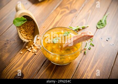 zuppa di piselli cotti con costolette affumicate in un piatto un tavolo di legno Foto Stock