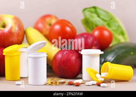 Pillole di integratori alimentari di fronte alla frutta e. verdure in background Foto Stock