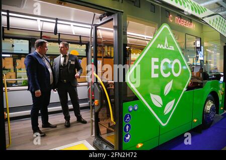 Mosca, Russia. 13 maggio 2021. I visitatori parlano su un autobus elettrico esposto durante la mostra internazionale ElectroTrans sul trasporto elettrico urbano a Mosca, Russia, 13 maggio 2021. La mostra durerà fino al 14 maggio. Credit: Alessandro Zemlianichenko Jr/Xinhua/Alamy Live News Foto Stock