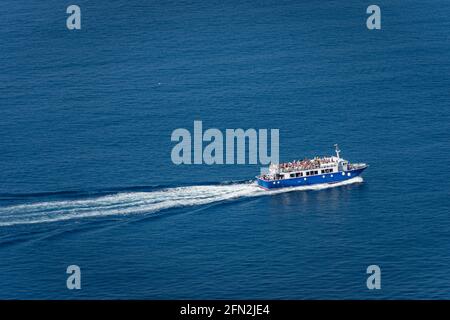 Traghetto blu con molti turisti a bordo, durante la navigazione verso le cinque Terre nel Mar Mediterraneo. Golfo di la Spezia, Liguria, Italia, Europa. Foto Stock