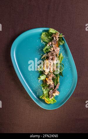 insalata con razzo di tonno e verdure su un piatto blu. Foto Stock