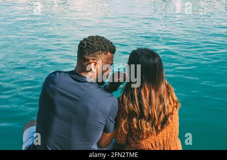 Coppia interrazziale che si coccola davanti alla vista mare Dal retro (ragazzo nero) Foto Stock