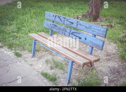 POZNAN, POLONIA - 26 ottobre 2016: Panca di parco in legno blu con erba verde Foto Stock