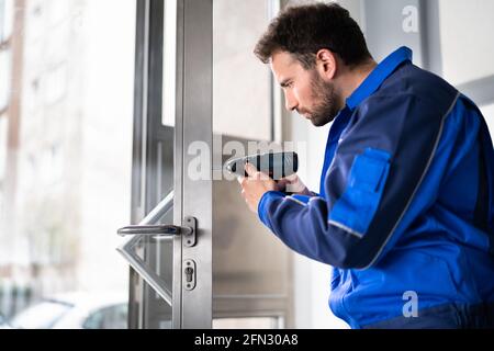 Fabbro uomo riparazione e sostituzione della serratura di metallo della porta Foto Stock