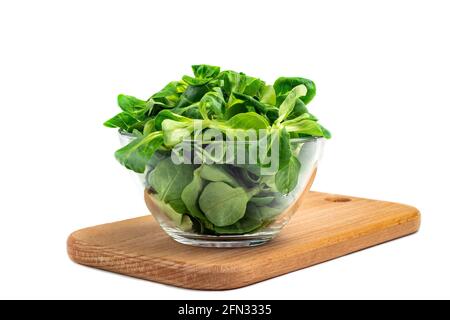 Foglie di insalata di fagioli Mung, insalata di mais in un recipiente di vetro su una tavola di legno, isolare. Miscela fresca di foglie verdi lavate (Valerianella locusta). Dieta e healt Foto Stock