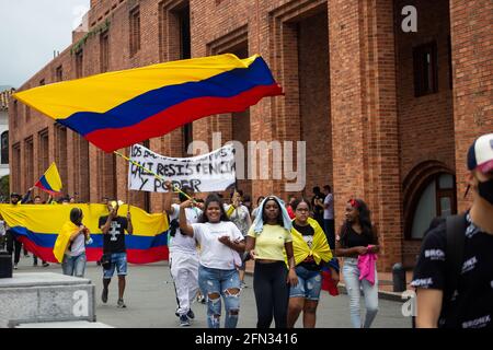 I manifestanti portano e fanno ondate bandiere colombiane durante le rivolte e le saccheggi nella città di Cali mentre i manifestanti si riuniscono durante il primo giorno di proteste anti-governative contro la riforma fiscale e la riforma sanitaria del presidente Ivan Duque nella città di Cali, Valle del Cauca, il 28 aprile 2021. Più tardi, in giornata, le manifestazioni rischiavano di disordini e diverse morti in casi di brutalità della polizia nel dipartimento della Valle del Cauca. Foto Stock