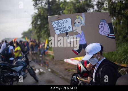 Un dimostratore porta un cartello con un cartone dell'ex presidente della Colombia Alvaro Uribe con un cartello che recita "No alla riforma fiscale di Duque", mentre i manifestanti si riuniscono durante il primo giorno di proteste anti-governative contro la riforma fiscale e la riforma sanitaria del presidente Ivan Duque a Yumbo; Valle del Cauca il 28 aprile 2021. Più tardi, in giornata, le manifestazioni rischiavano di disordini e diverse morti in casi di brutalità della polizia nel dipartimento della Valle del Cauca. Foto Stock