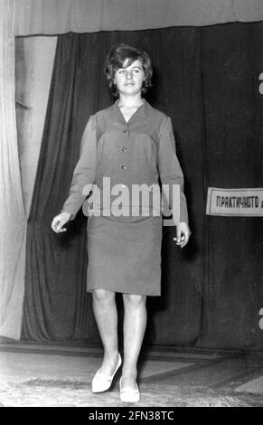 Modello femminile su rampa di piattaforma che mostra la nuova collezione di abbigliamento in una sfilata di moda indoor nel 1960s, Bulgaria, Europa orientale Foto Stock