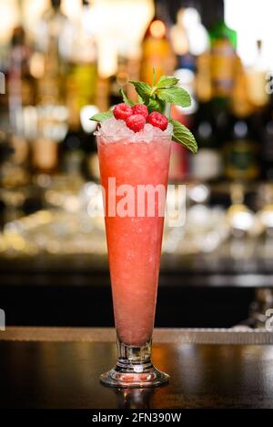 Cocktail rosa con ghiaccio tritato, lamponi e menta in alto vetro Foto Stock