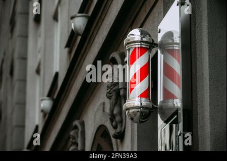 Barbiere segno rosso e bianco sullo sfondo della città Foto Stock
