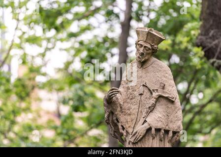 Monumento nel giardino del Castello di Brno. Monumento in pietra ad un uomo sullo sfondo di alberi di primavera. Foto Stock