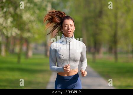 Donna che corre nel parco la mattina presto. Donna attraente che si adatta e sano. Concetto di stile di vita sano. Foto Stock