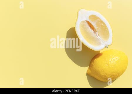 Due tagli a metà di limone con ombra su sfondo giallo. Cibo sano, viaggio o vacanza concetto Foto Stock