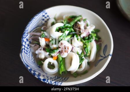 Il basilico fritto lascia il calamaro in una ciotola bianca Foto Stock