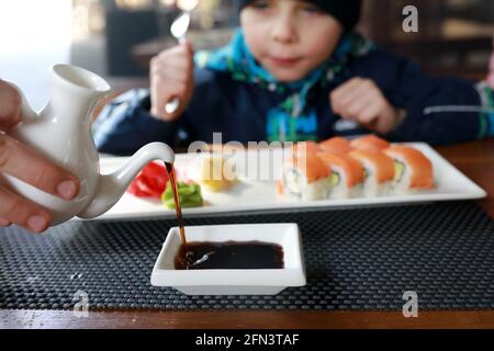 Persona che versa la salsa di soia per il sushi al ristorante Foto Stock