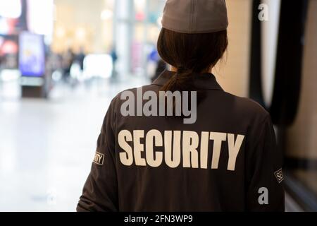 Vista posteriore di una guardia di sicurezza femminile con pattugliamento uniforme in una zona residenziale Foto Stock