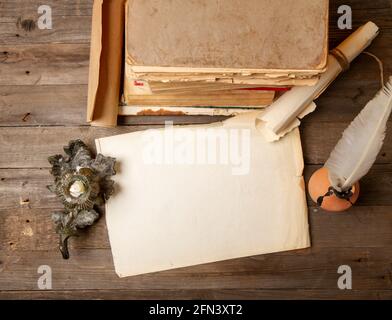 Vintage sfondo medievale con libri rotoli inkwell e penna di quill su tavolo di legno grezzo Foto Stock