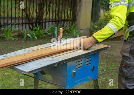 Un uomo taglia il legno su una sega circolare. Lavori di costruzione nel cortile. Foto Stock