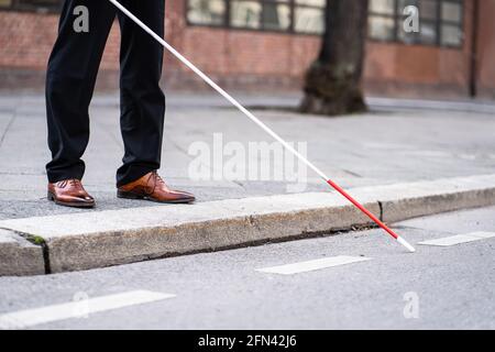 Uomo cieco che cammina con cane Stick su strada Foto Stock