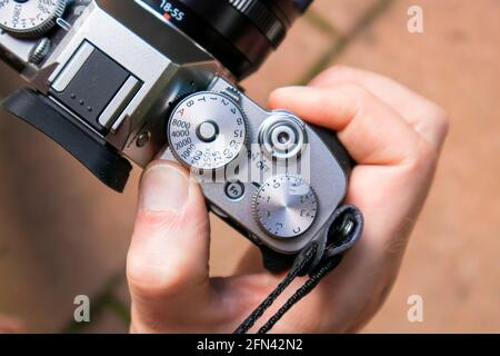 Primo piano di un corpo di fotocamera mirrorless con obiettivo tenuto da una mano di persona Foto Stock