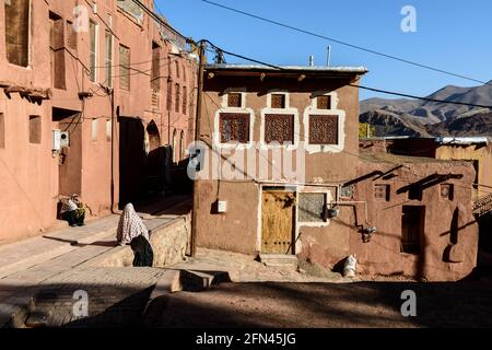 Due donne residenti in costume tradizionale godendo il sole d'autunno nel villaggio antico Abyaneh, Provincia di Isfahan, Iran Foto Stock