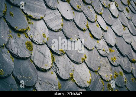 tetto con vecchie piastrelle di colore scuro, tra nero e grigio. Creare una ripetizione con texture da una prospettiva angolata Foto Stock