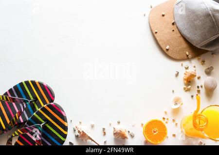 scarpe da spiaggia, cappello da baseball, succhi e conchiglie - accessori da spiaggia per le vacanze estive su sfondo bianco Foto Stock