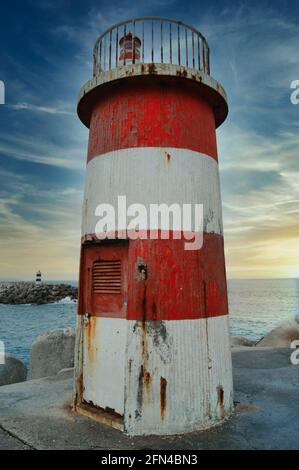 Vecchio piccolo faro in disuso. Faro abbandonato con strisce rosse e bianche. Foto Stock