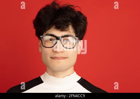 Ritratto dell'uomo asiatico isolato su sfondo rosso dello studio con copyspace Foto Stock