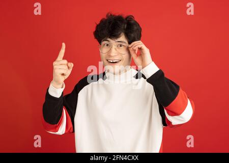 Ritratto dell'uomo asiatico isolato su sfondo rosso dello studio con copyspace Foto Stock