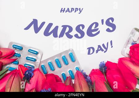 Biglietto d'auguri con fiori e pillole con iscrizione Happy Nurse's. Giorno su bianco Foto Stock