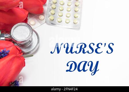 Biglietto d'auguri con fiori e pillole con iscrizione Happy Nurse's. Giorno su bianco Foto Stock