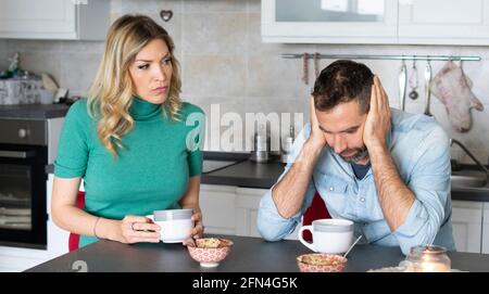 Donna sospetta guarda il suo ragazzo preoccupato. L'aspetto drammatico di una moglie gelosa che scolgiva marito frustrato durante la colazione. Donna bossy. Foto Stock