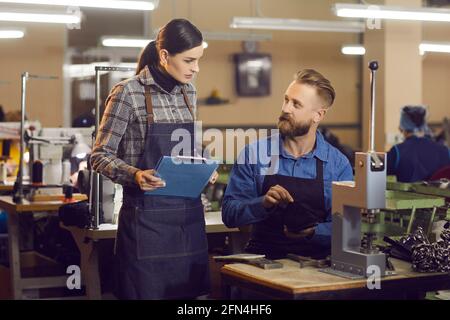 Responsabile della fabbrica di calzature che discute il processo di produzione delle calzature con un dipendente Foto Stock