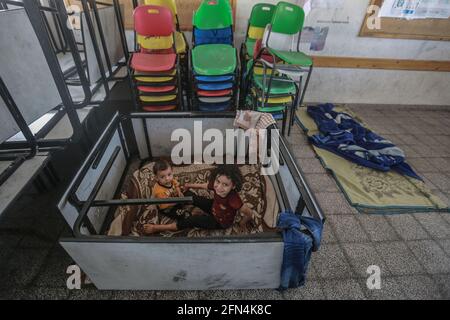 Gaza, territori palestinesi. 14 maggio 2021. I bambini si siedono all'interno di una scuola dell'ONU nella città di Gaza, dove le famiglie palestinesi si rifugiano dopo aver fuggito dalle loro case nel quartiere di Shejaiya e nella città di Beit Lahia durante gli attacchi aerei israeliani, in mezzo all'escalation della violenza israelo-palestinese. Credit: Mohammed Talatene/dpa/Alamy Live News Foto Stock