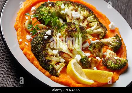 bistecca di broccoli alla griglia con purè di zucca con formaggio feta sbriciolato, ricetta vegetariana, vista orizzontale dall'alto Foto Stock