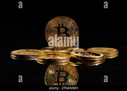 Monete d'oro closeup con logo bitcoin. Leader nella criptovaluta Bitcoin BTC su una cima di monete contro la superficie nera specchio. Un mucchio di decentralizzati Foto Stock