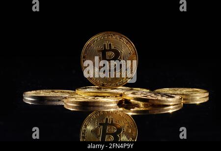 Monete d'oro closeup con logo bitcoin. Leader nella criptovaluta Bitcoin BTC su una cima di monete contro la superficie nera specchio. Un mucchio di decentralizzati Foto Stock