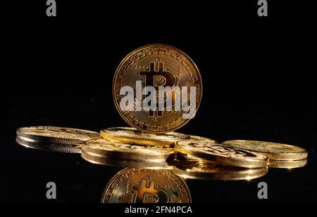 Monete d'oro closeup con logo bitcoin. Leader nella criptovaluta Bitcoin BTC su una cima di monete contro la superficie nera specchio. Un mucchio di decentralizzati Foto Stock